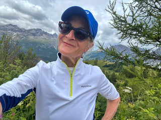 Woman in a mountainous landscape wearing a white moorlow pullover jacket.