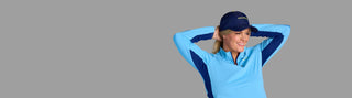 Waist-up shot of woman adjusting her hair while wearing the moorlow Performance Hat in Midnight Blue and light blue Brooksie pullover—stylish, functional pickleball outfit designed for confident movement and comfort.