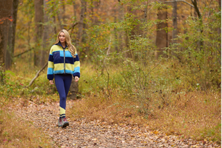 Woman walking on a path in a forest wearing moorlow zip fleece and leggings.