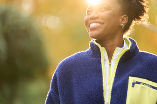 Woman wearing moorlow zip fleece jacket with a blurred outdoor background