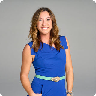Portrait of Sondra Hoffman, co-founder of moorlow, in tailored blue jumpsuit with aqua belt—fashion-industry expert leading with confident, stylish design for pickleball.